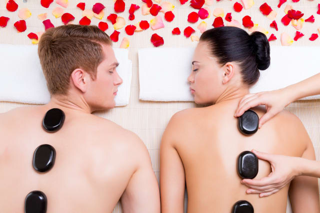 Beautiful couple relaxing in spa salon with hot stones on body. Beauty treatment therapy. modelage du monde spa