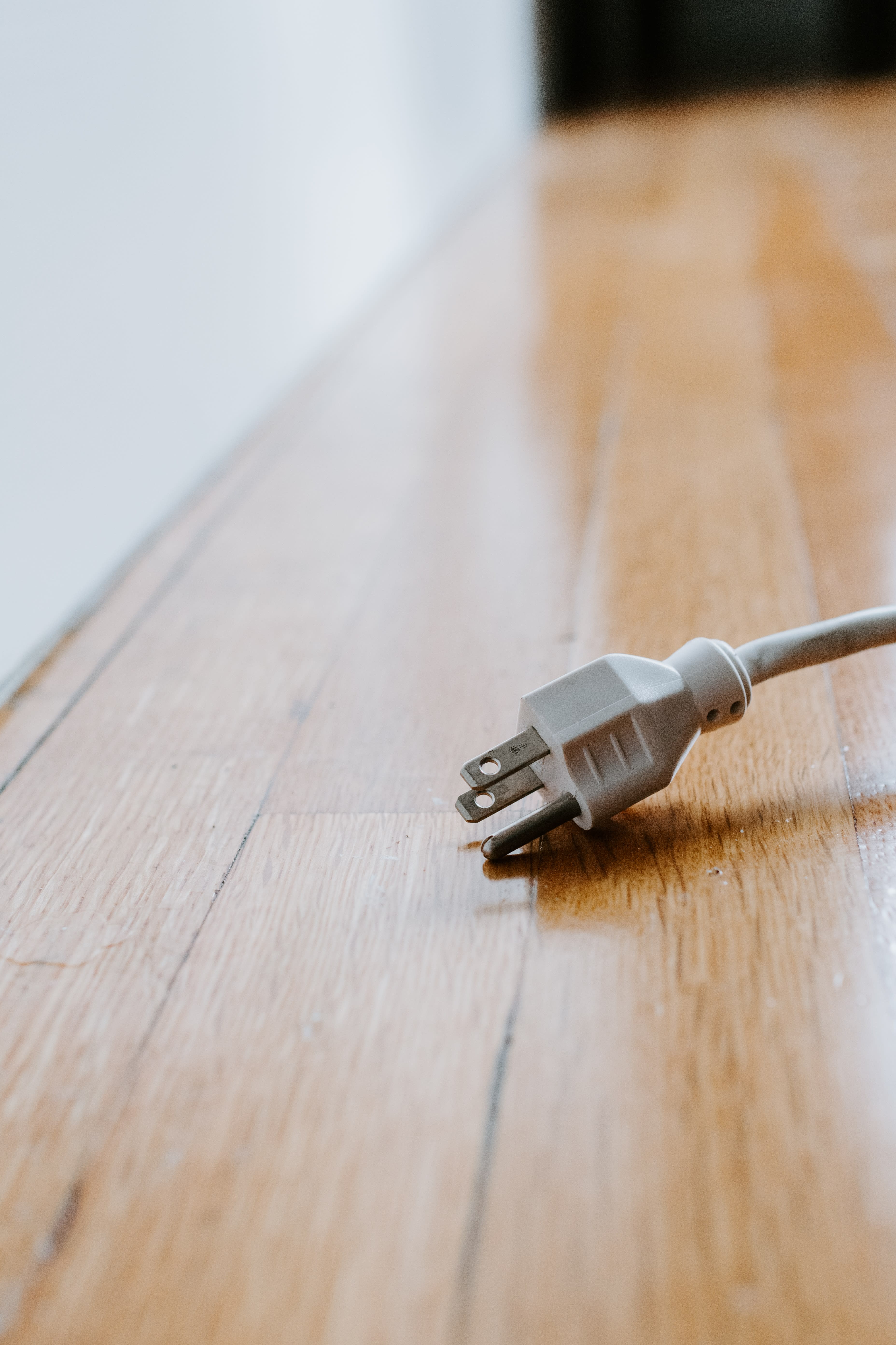 An unplugged power cable, resting on wooden floor