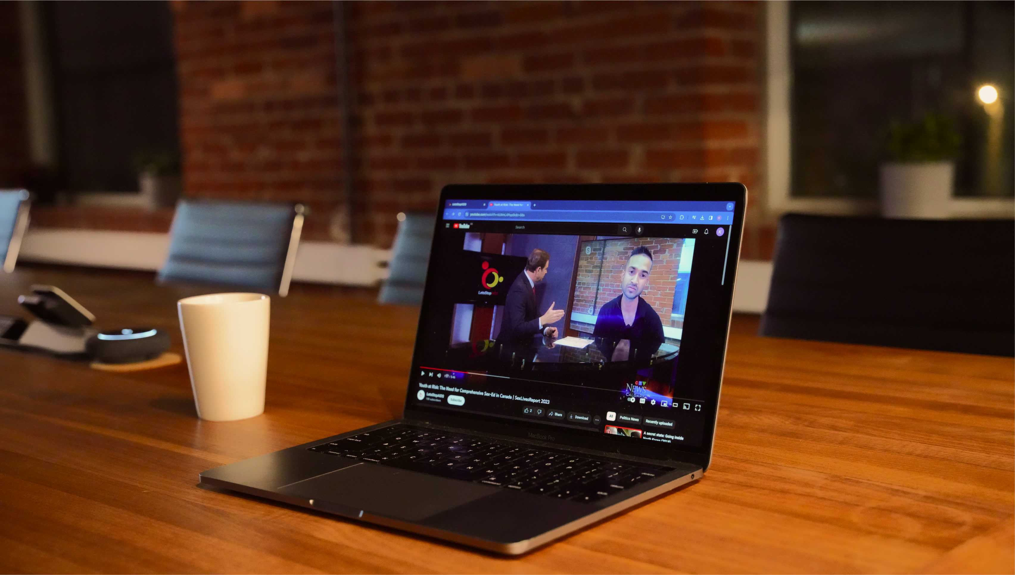 A laptop is placed on the table, showing an interview with our CEO, Shamin Mohamed Jr.