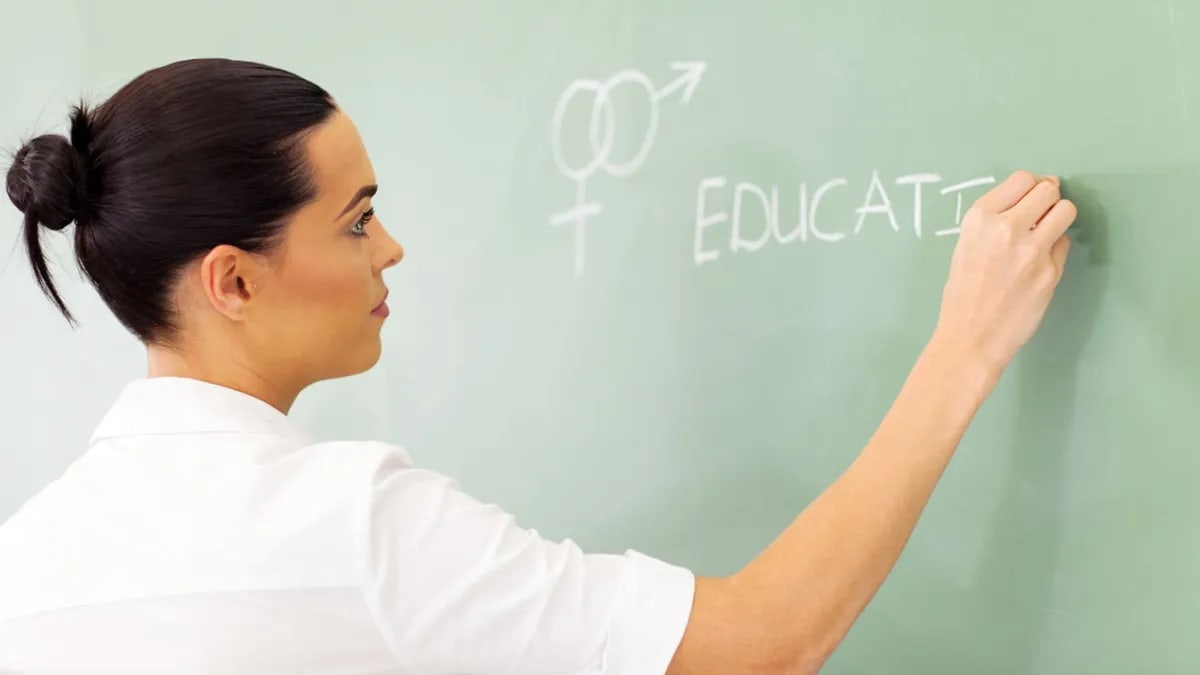 Teacher writing on a chalkboard teaching about SexEd 