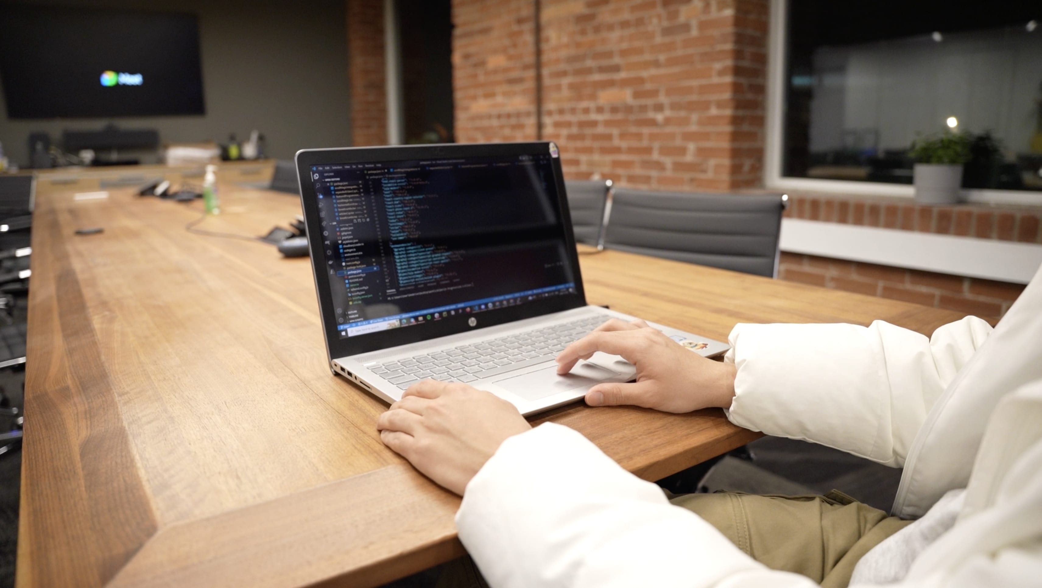 A laptop on the desk in a boardroom showcasing code, worked on by a developer.