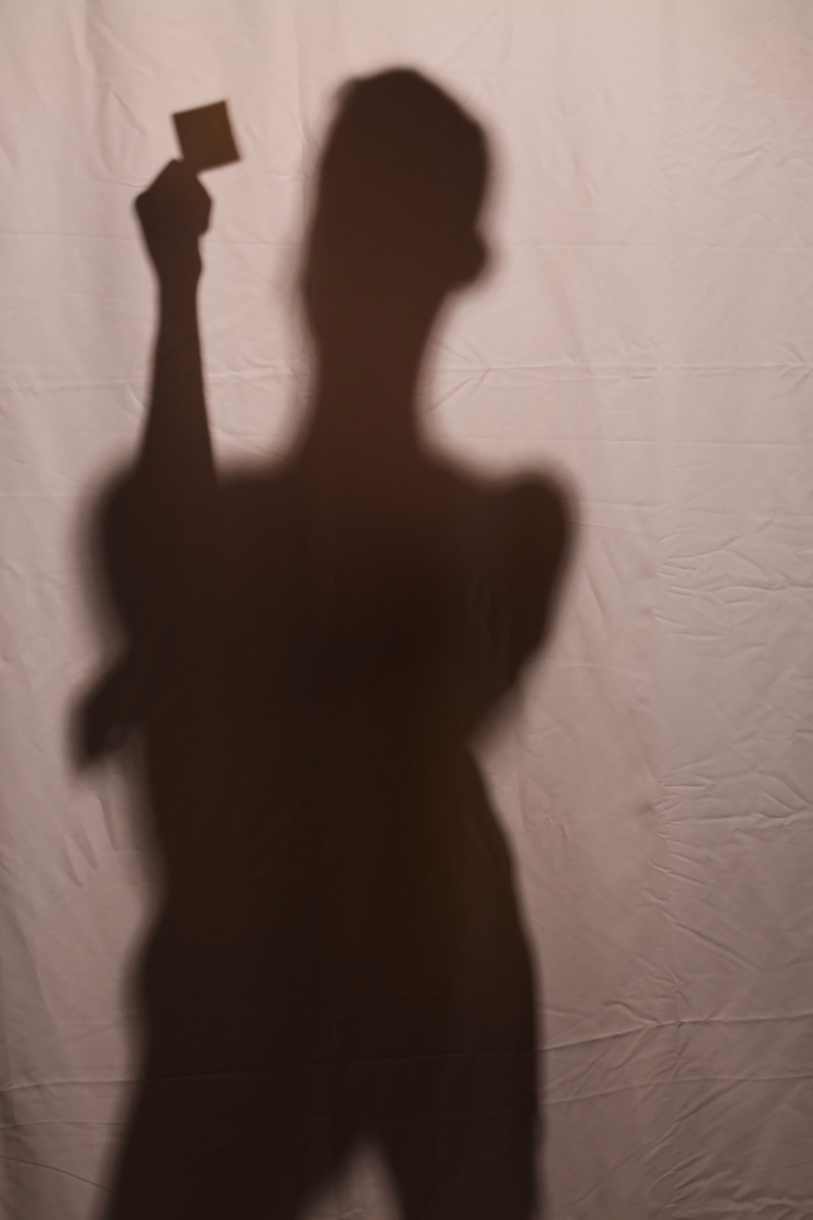 A silhouette of a male figure grasping a condom package, casting a distinct shadow.