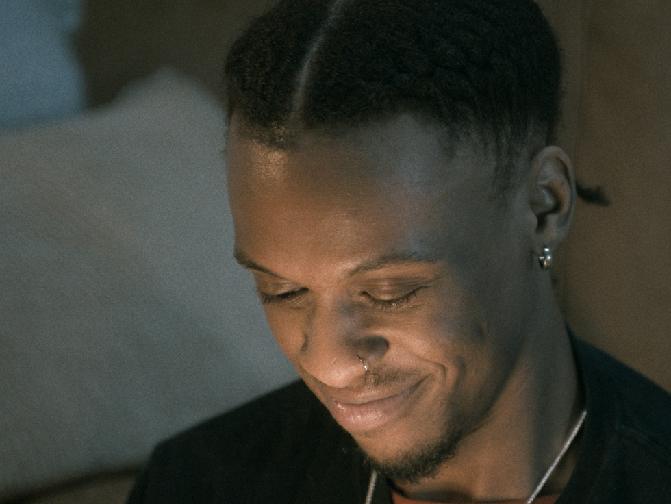 A guy smiling while looking at his phone, appearing pleased by what he sees.