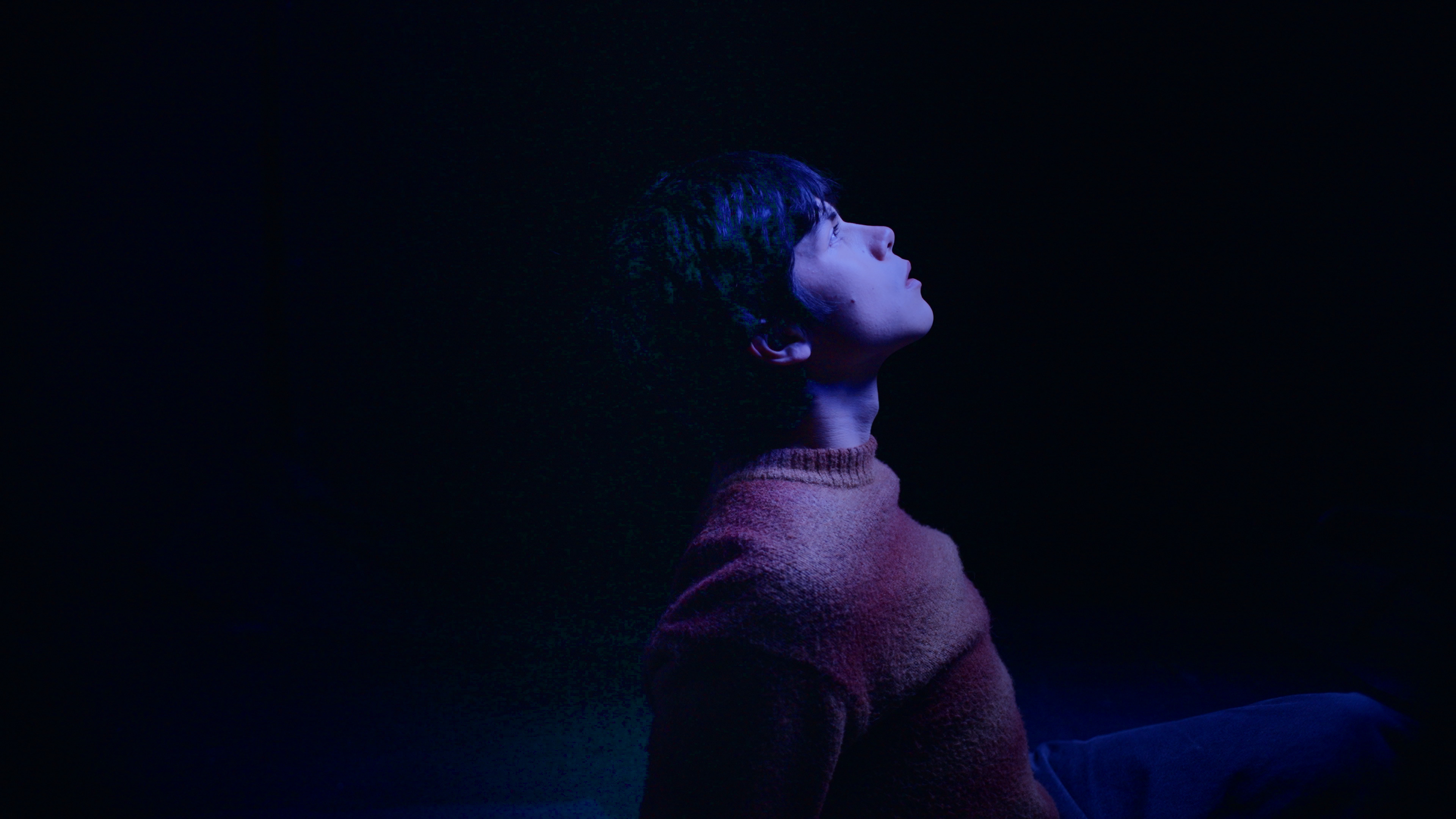 A guy looking up in a dark room.