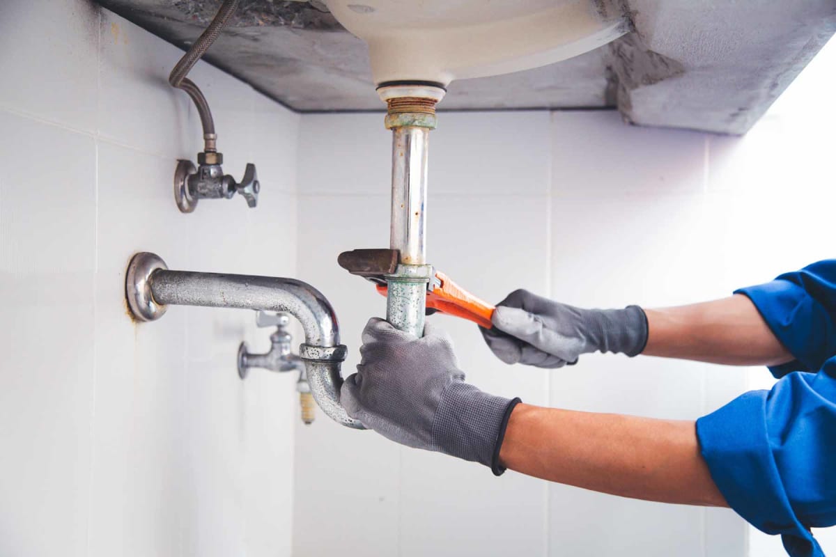 https://res.cloudinary.com/liaison-inc/image/upload/f_auto/q_auto,w_1200/v1695145245/content/homeguide/homeguide-plumber-using-wrench-to-work-on-clogged-drain-pipe.jpg