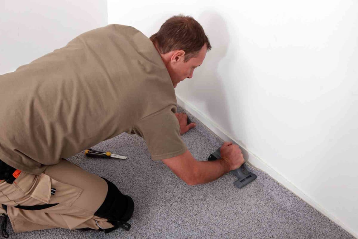 Installer Using Carpet Stretcher On New Bedroom Floor Stock Photo