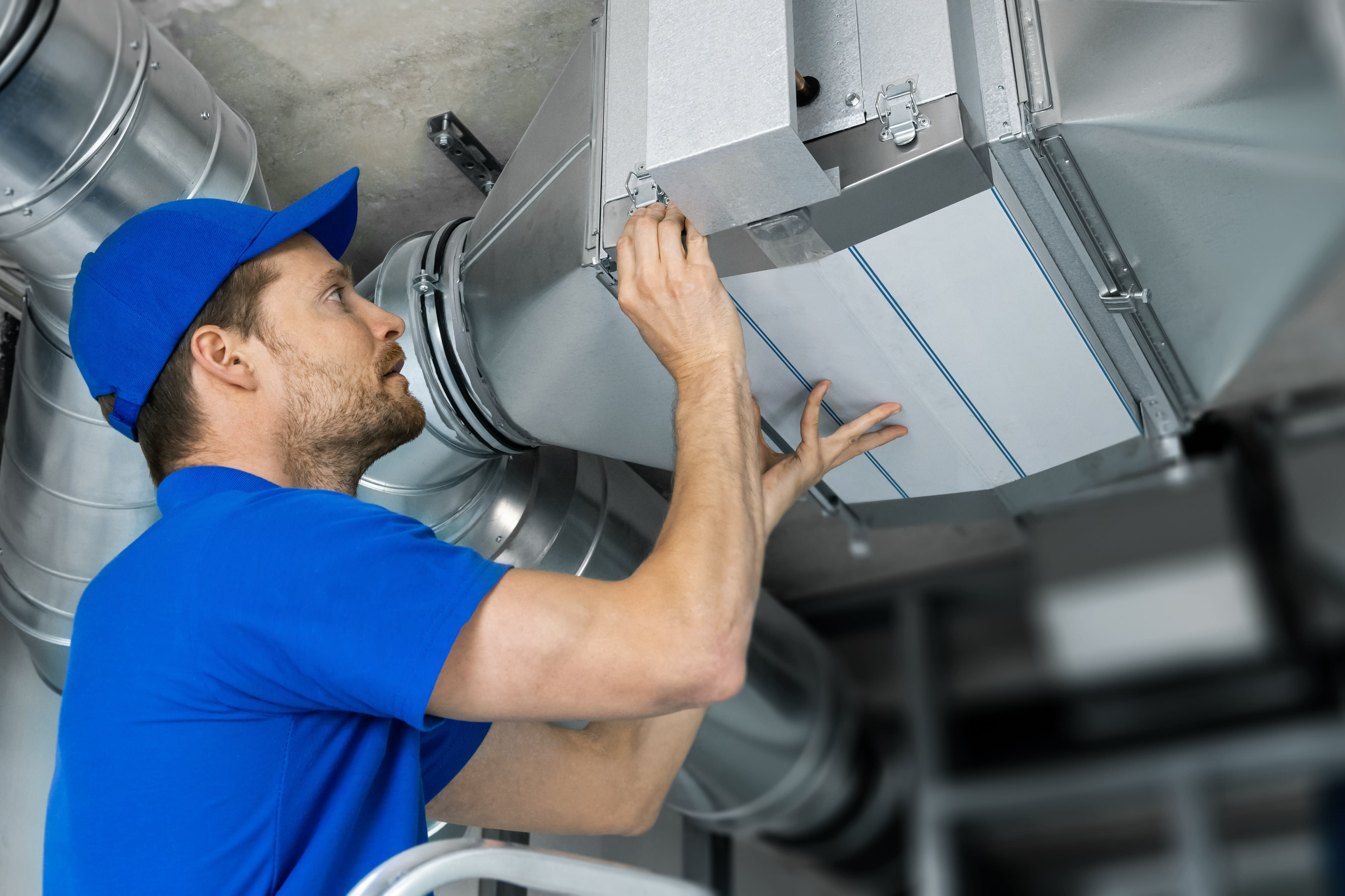 HVAC technician installing whole-home air purifier.