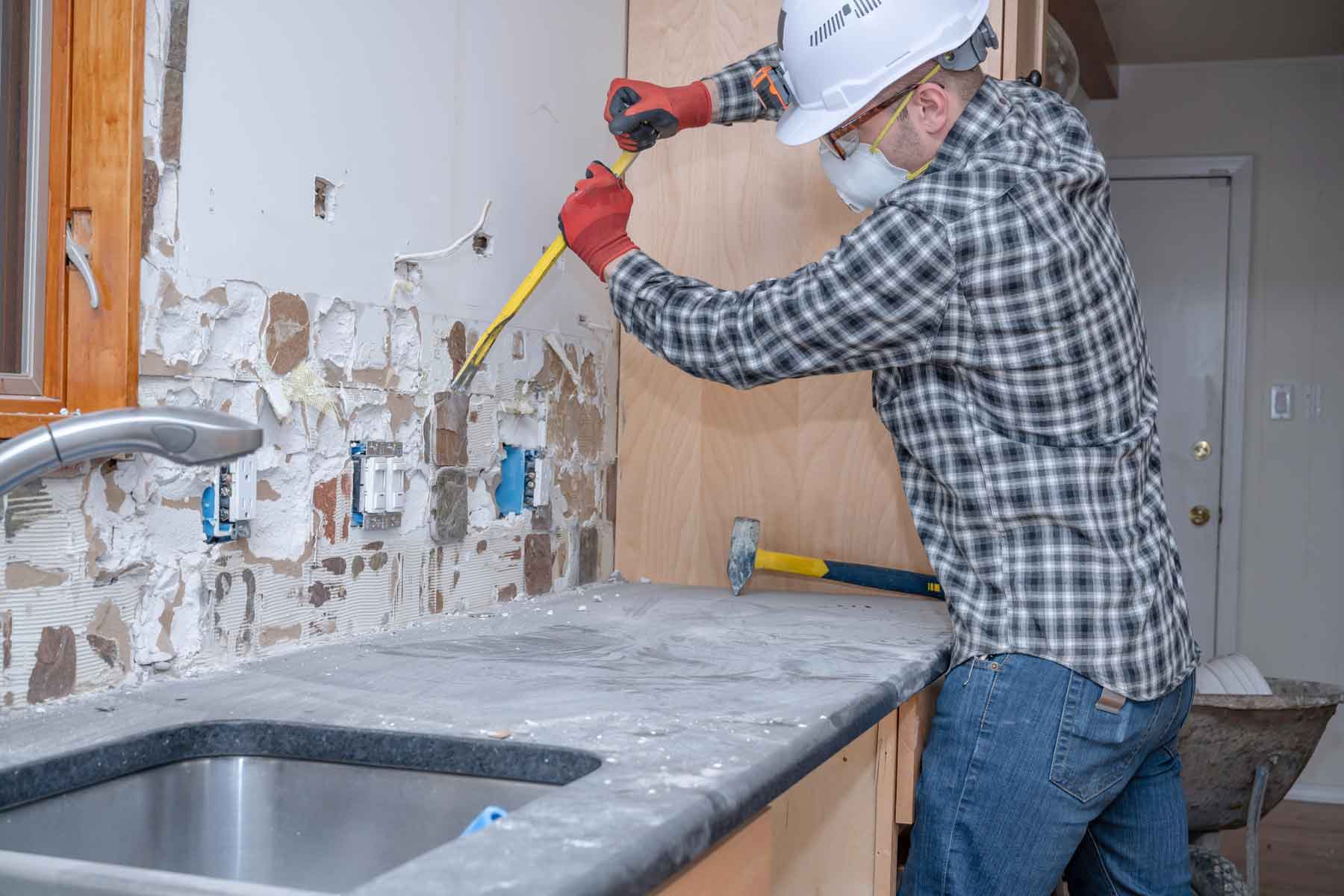 Homeguide Worker Removing Tile Backsplash During Kitchen Demolition 