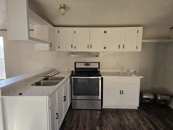 Kitchen update. The cabinets were refinished from old brown to white with black handles, the sink was replaced, a backsplash detail was added above the sink, and the flooring was completely redone