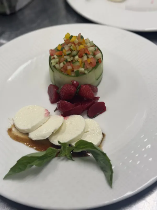 A delicate cucumber wrap holds a crisp medley of bell peppers, tomatoes, and cucumbers, paired with juicy raspberries and creamy mozzarella