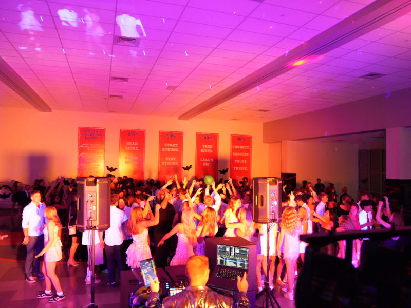 Students on a packed dance floor under colored lights
