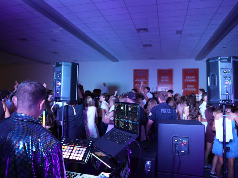 Packed high school dance floor with DJ booth and lighting