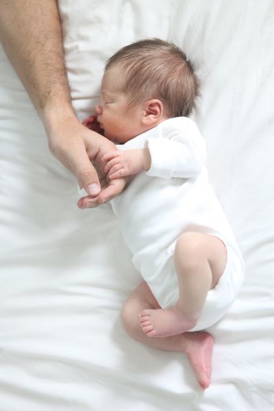 Father holding his baby boy's hand.