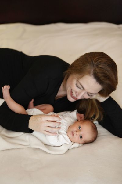 Mother lying on the bed with her baby girl. 