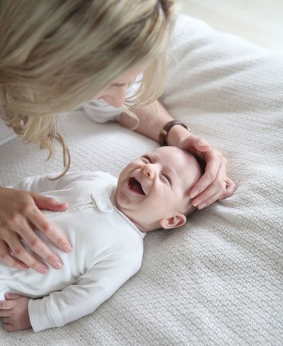 A mother with her baby boy laughing while he is looking at her.