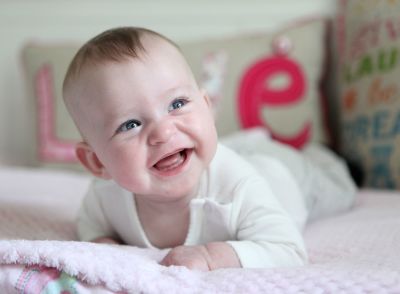 A little girl lying on her tummy, laughing.