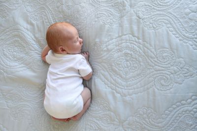 A baby boy with red hair sleeping on his stomach.