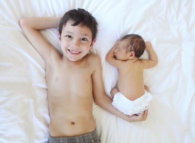 Brother and his newborn baby brother on the bed.