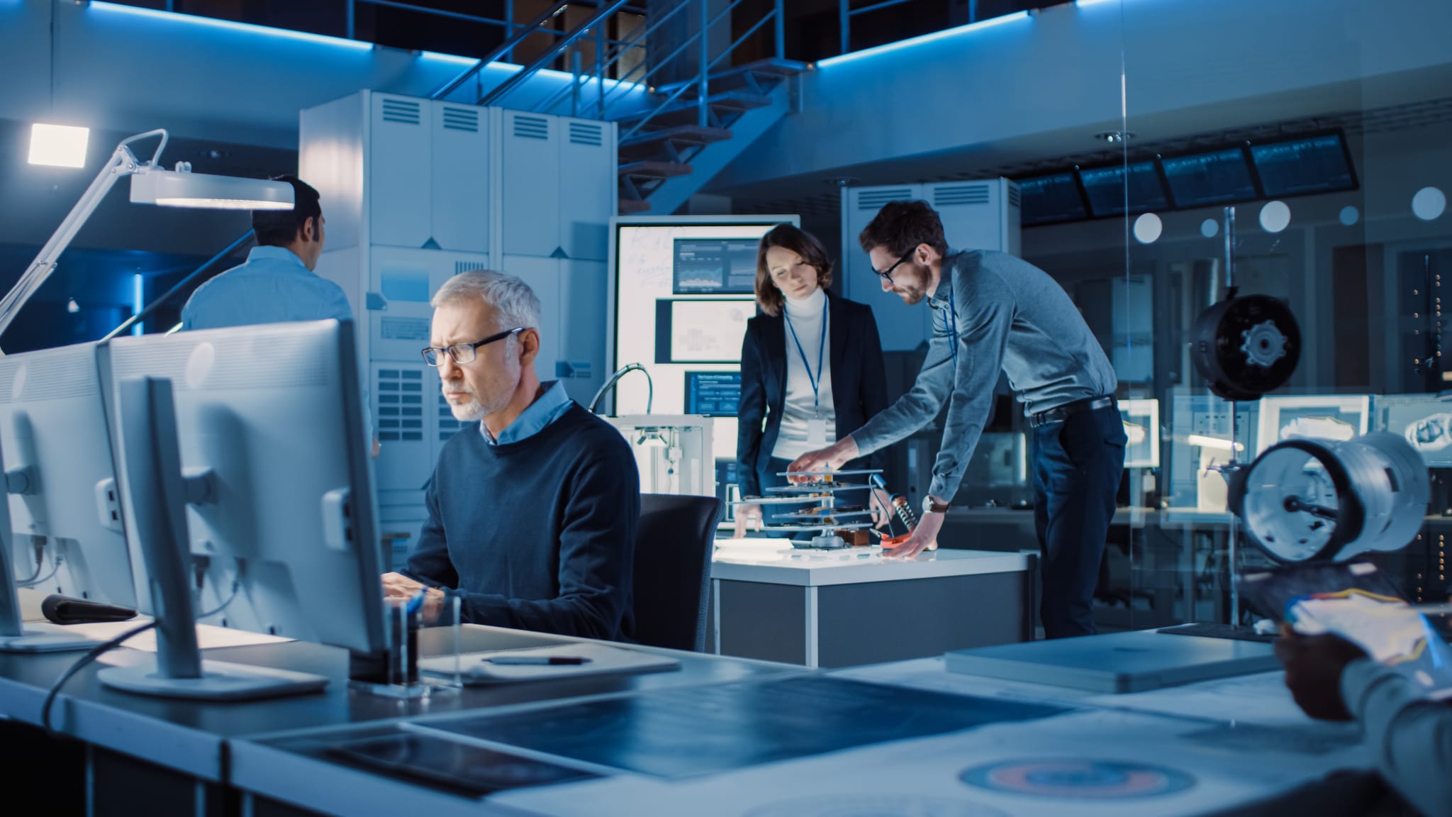 Diverse International Team of Industrial Engineers and Scientists Working in Research Laboratory and Development Center. People Working with 3D Printing, Using Computers, Designing Hardware Diverse International Team of Industrial Engineers and Scientists Working in Research Laboratory and Development Center. People Working with 3D Printing, Using Computers, Designing Hardware
