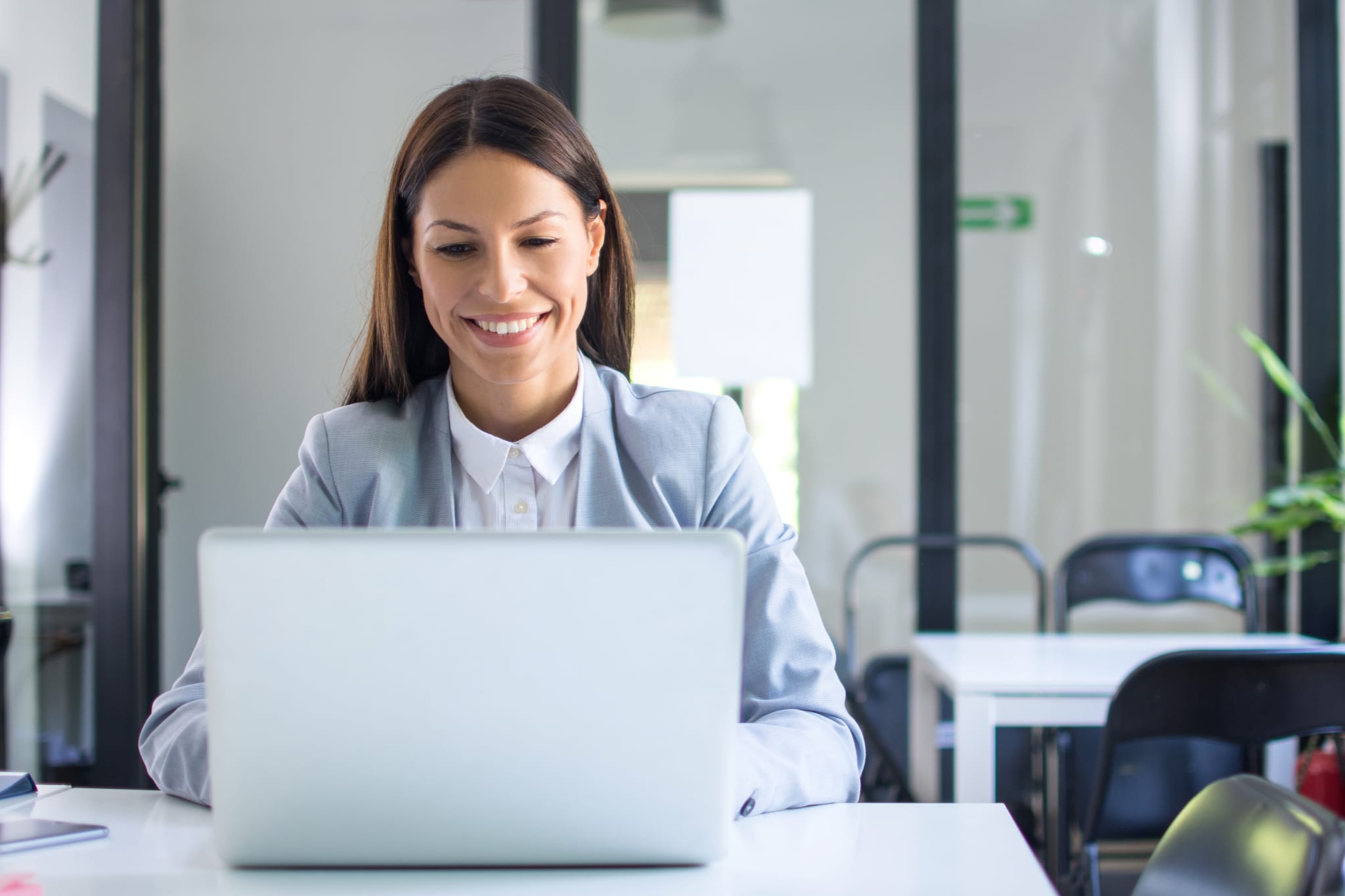 Beautiful young businesswoman in formal wear using laptop in office Beautiful young businesswoman in formal wear using laptop in office