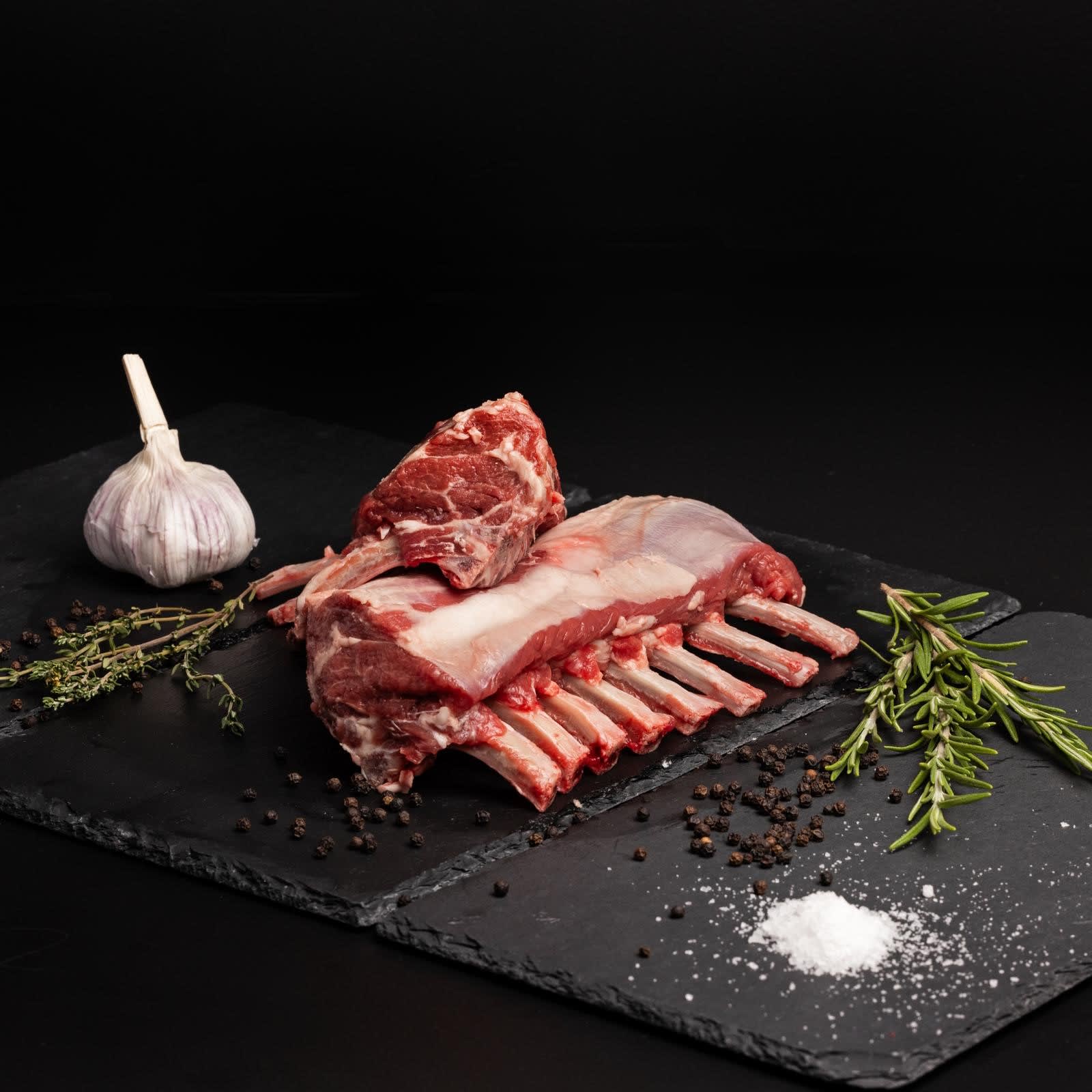 Lamsrack op een bord met knoflook en groente.