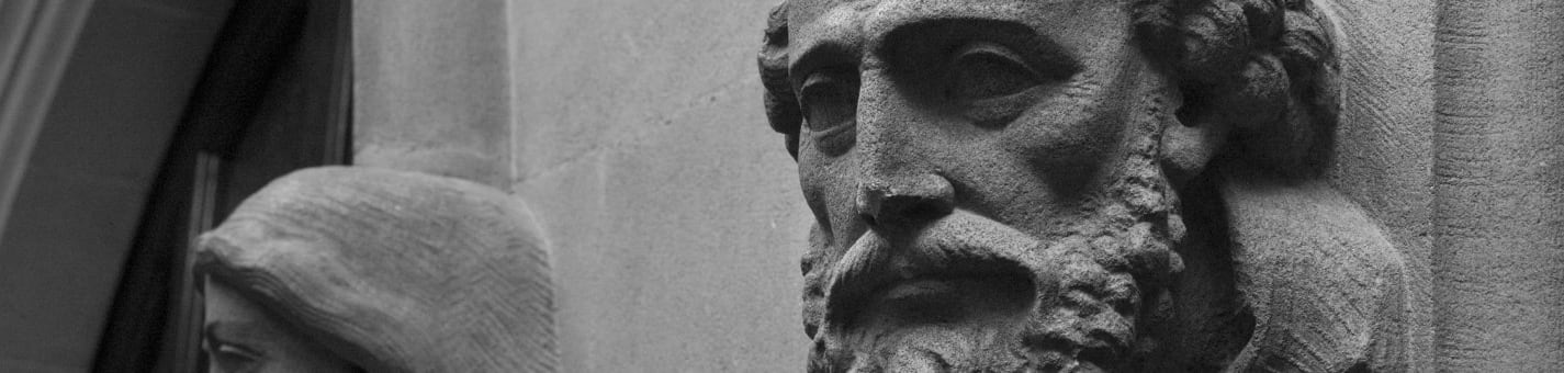 Close up of a carved stone face of a bearded man on a wall of the Inn