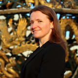 Headshot of Margaret McGowan-Smyth wearing a black suit jacket and standing in front of the Celestial Sphere Woodrow Wilson Memorial, Palais des Nations, Geneva