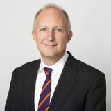 Headshot of Samuel Townend KC in front of a plain background wearing a suit and tie