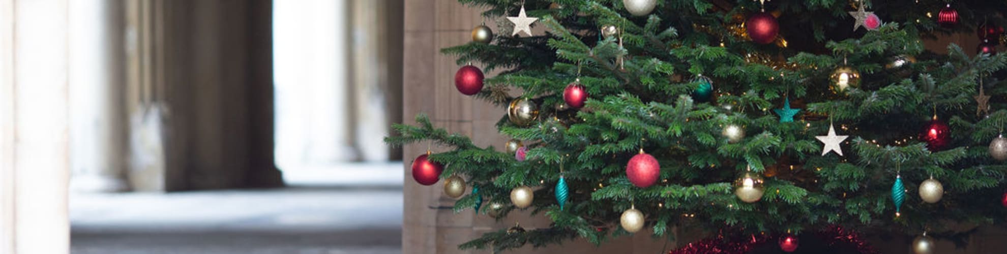 A Christmas tree adorned with red and gold baubles alongside gold and green stars, stood in the Undercroft of Lincoln's Inn.