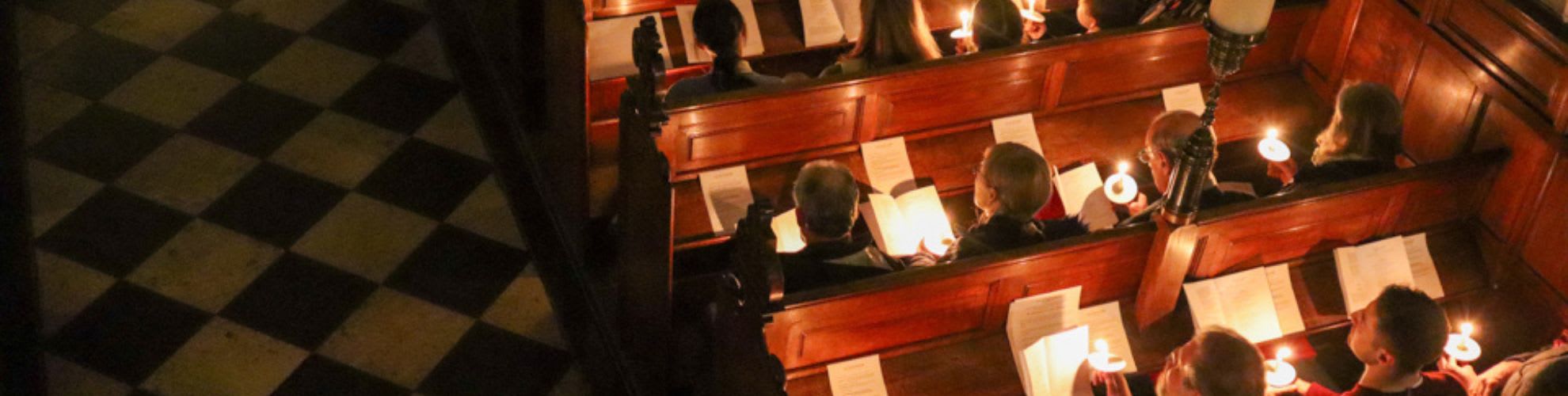 Attendees at the Chapel's Carol service sitting in the pews with soft lighting.