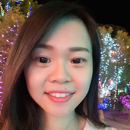 A selfie of Celynn Mong. She is smilin, has long very dark brown hair, and is in front of Christmas lights