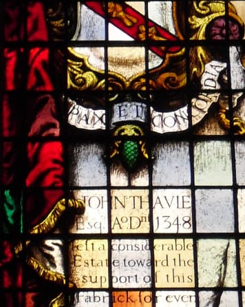 A stained glass window decorated with a coat of arms and an inscription.