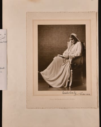 Sepia photograph of Cornelia Sorabji sat in a chair, reading a book. The photograph is signed.