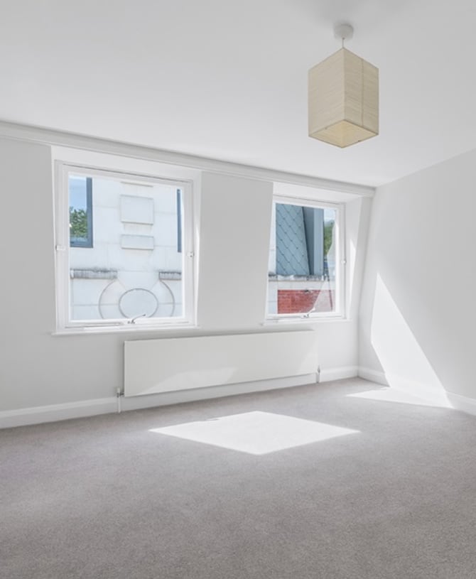 Unfurnished modern living space with neutral toned carpet.