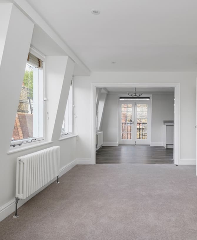 Unfurnished modern living space featuring neutral toned carpet and polished flooring.