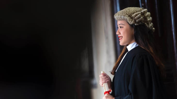 Student posing for Call Day photo in wig and gown with certificate