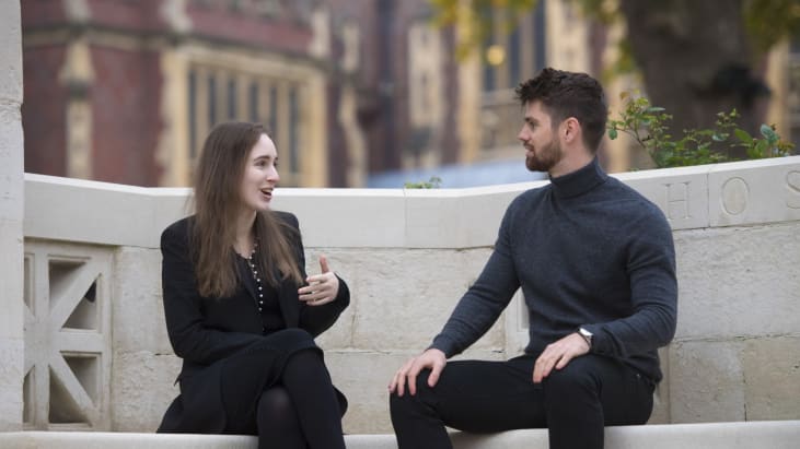 Two people chat in animated fashion on a bench in Lincoln's Inn.