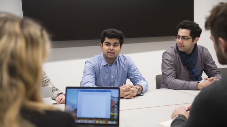 Barristers sitting around a board table in the Ashworth Centre having a meeting, laptop on table