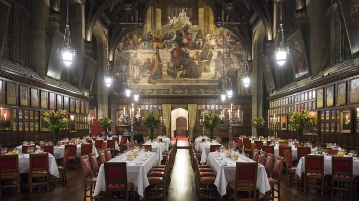 The Great Hall of Lincoln's Inn, with tables laid with white tablecloths and decorated with bouquets of flowers.