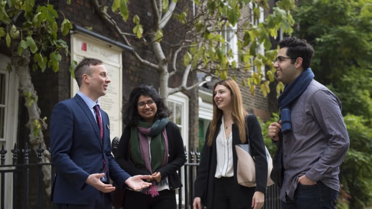 3 students in front of wisteria in New Square being given a tour of Lincoln's Inn