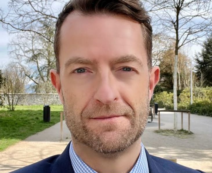 Chris Loweth in a park, wearing a blue suit