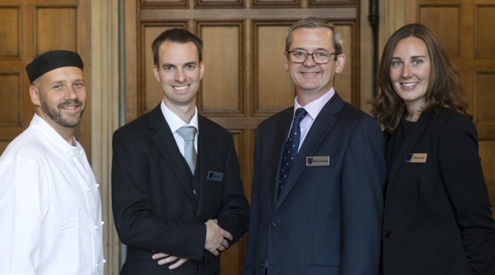 Four member of management team posing in front of historic building