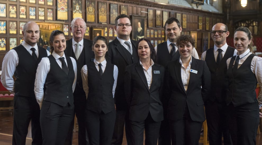 Ten member of front of house team posing for photo in historic hall