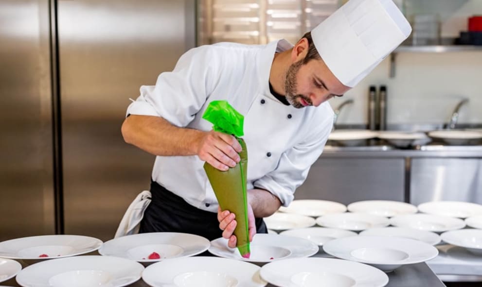 A chef plating dishes in kitchen