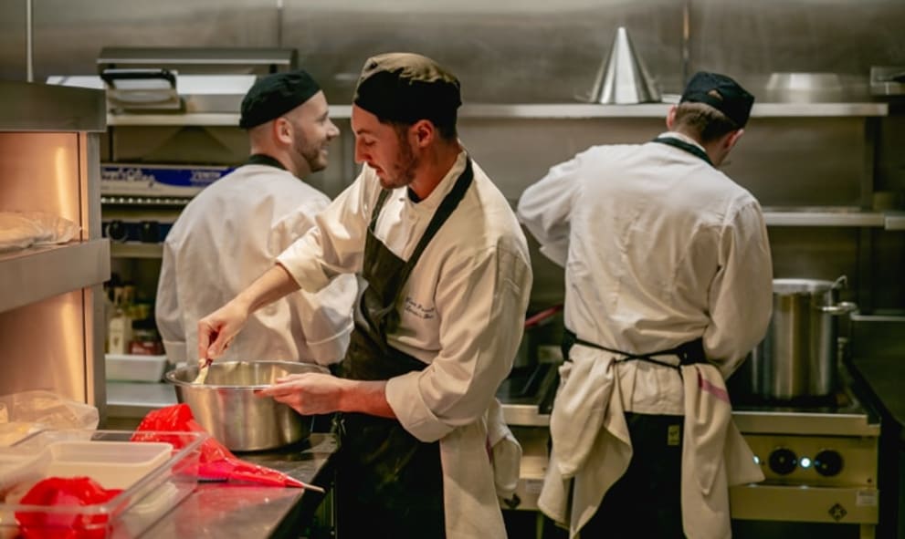Three chefs preparing food in kitchen