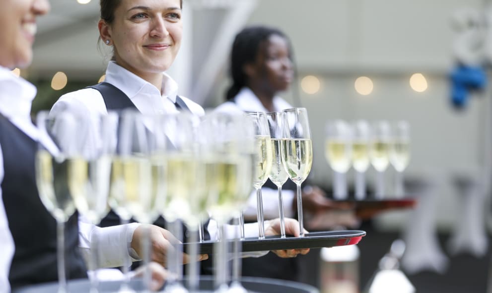 Servers holding trays of wine glasses for an outdoor event