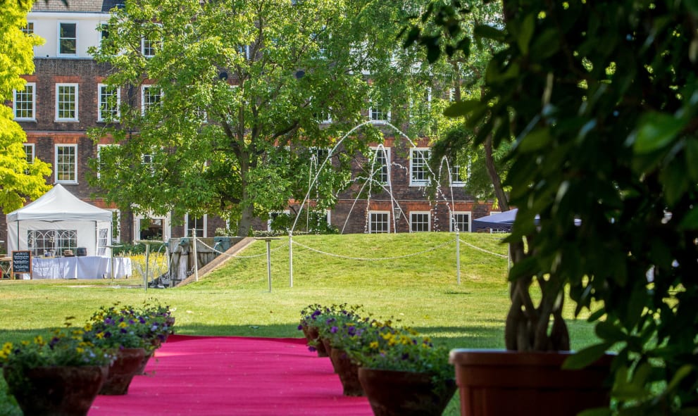 Historic garden set up for summer party with red carpet lined with flowers