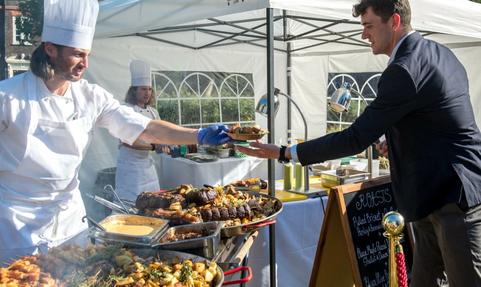 Chef handing food to a guest at a outdoor summer party