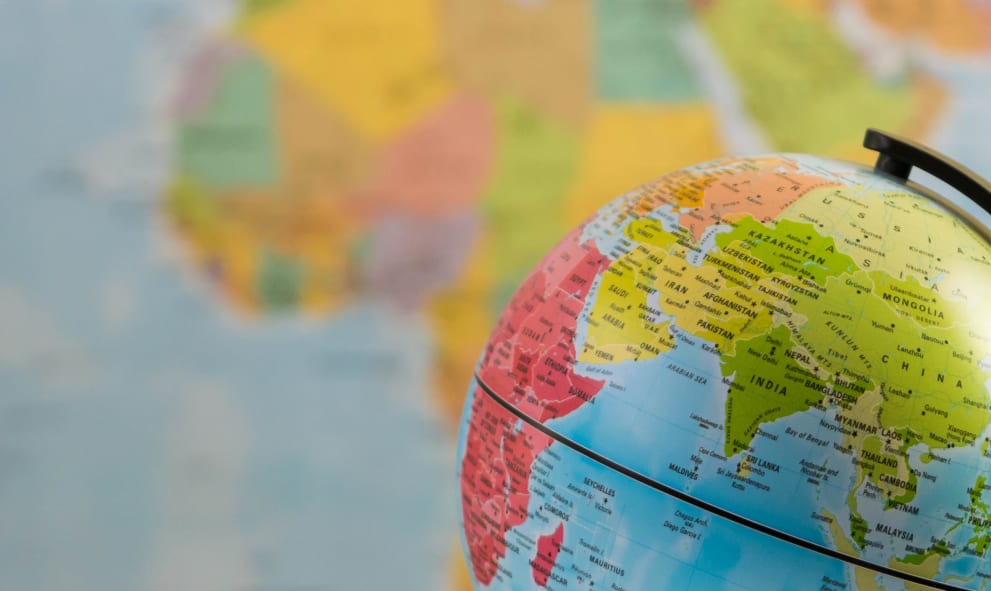 an earth globe focused on India with a blurred world map background