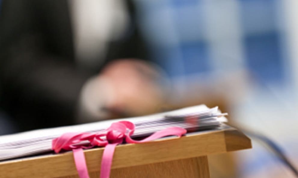 legal documents in foreground with blurred person in barrister attire in background
